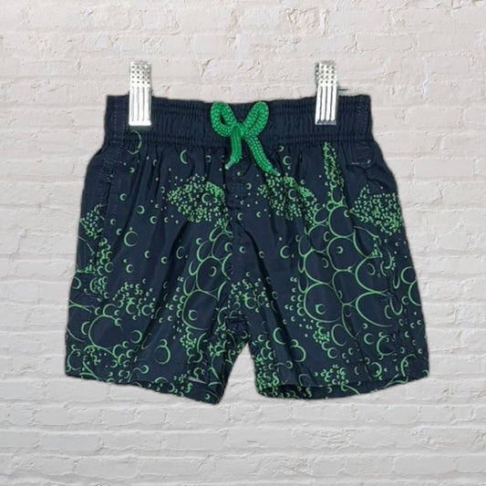 Navy swim shorts with green graphic pattern and green drawstring, displayed on a hanger.