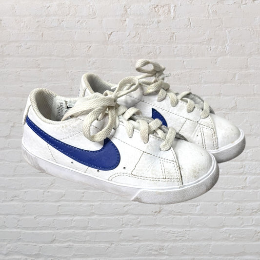 Pair of white Nike kids sneakers with blue swoosh logo and laces.