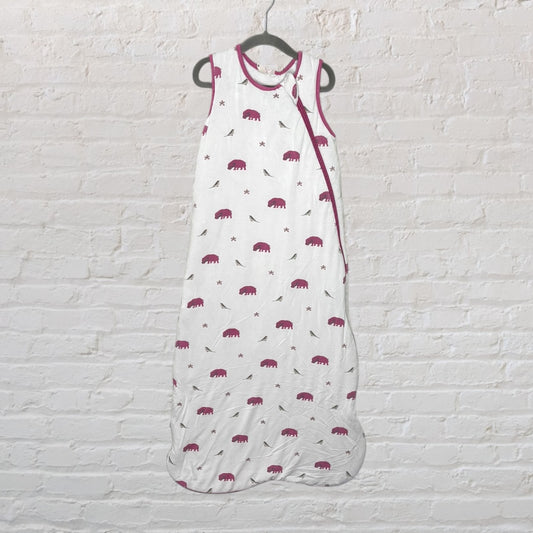 White baby sleeping bag with pink elephant print, hanging against a brick wall.