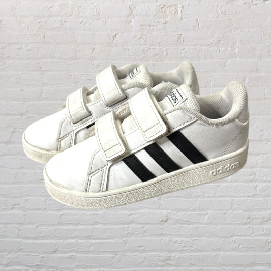 White Adidas sneakers with velcro straps and black stripes, side view.