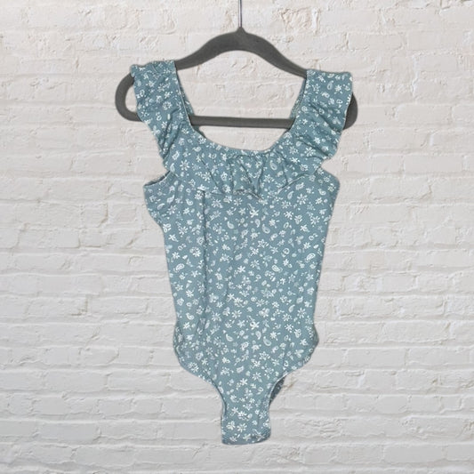 Blue floral print bodysuit with ruffled details on a hanger, featuring white floral patterns.