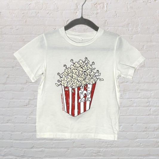 White T-shirt with a popcorn graphic design and red-striped container by Stella McCartney.