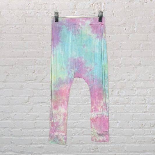 Multicolour pastel tie-dye leggings hanging on a white brick wall.