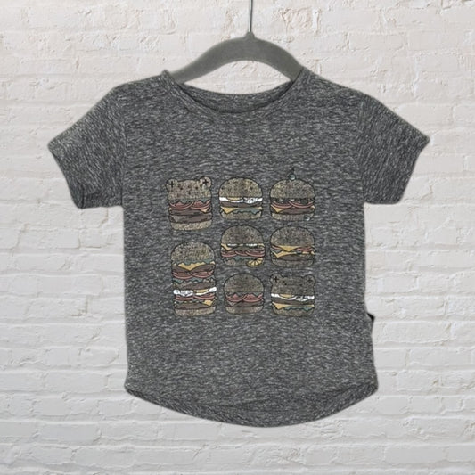 Grey short-sleeved T-shirt with multiple cartoon burgers graphic on the front, hanging on a hanger.