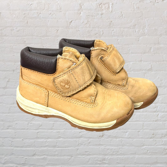 A pair of tan Timberland Velcro strap boots with brown padded collars and visible logo.